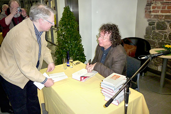 Foto zu einer Veranstaltung: Ingo Schulze signiert ein von ihm geschriebenes Buch.